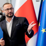 Pan Tomasz Zjawiony - Prezes Regionalnej Izby Gospodarczej przemawia do mikrofonu, w tle flaga Polski oraz Unii Europejskiej.